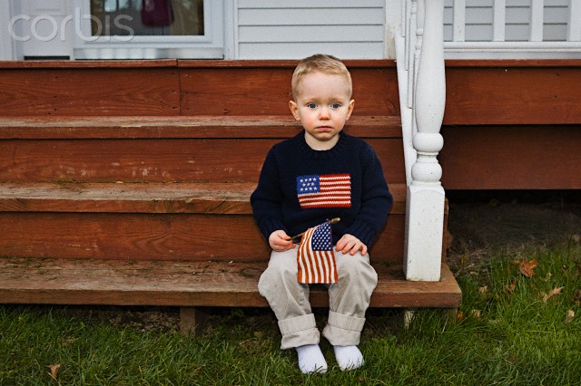 Little boy holding american flag sitting on porch